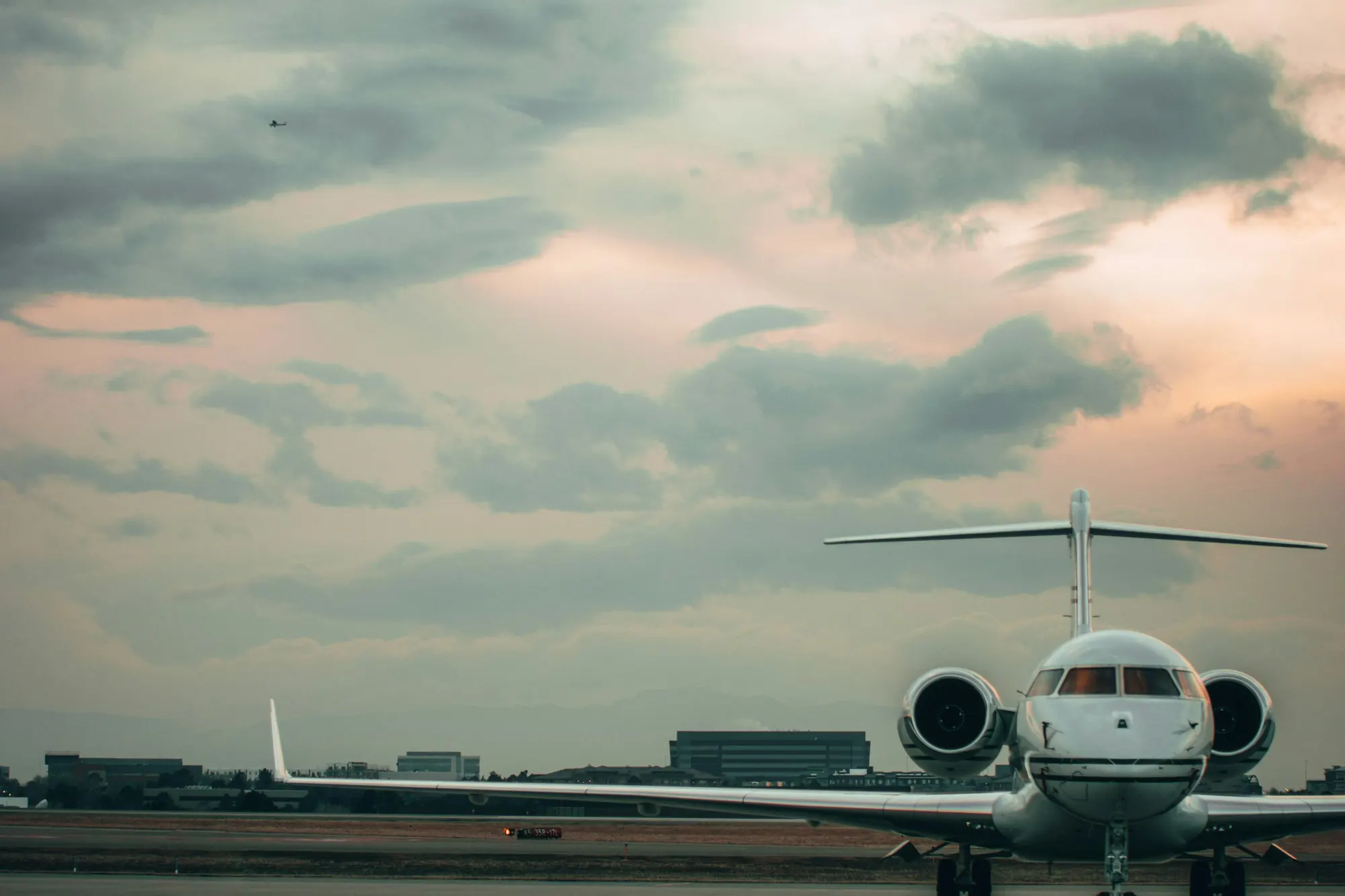 A large business jet on the ramp at dusk under a dramatic sky