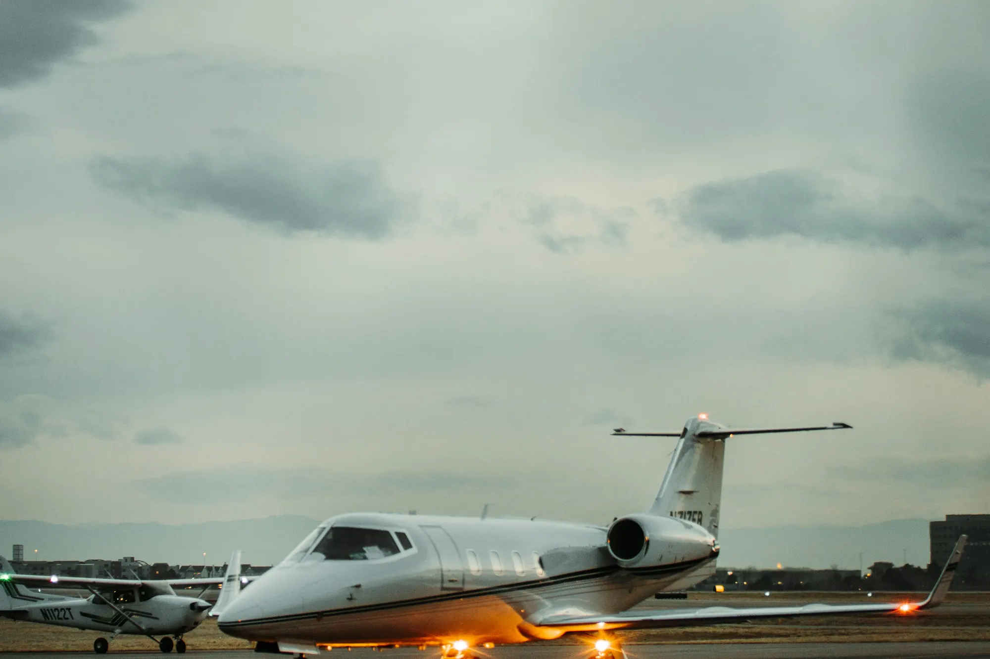 A light business jet on a wet runway under a dark sky