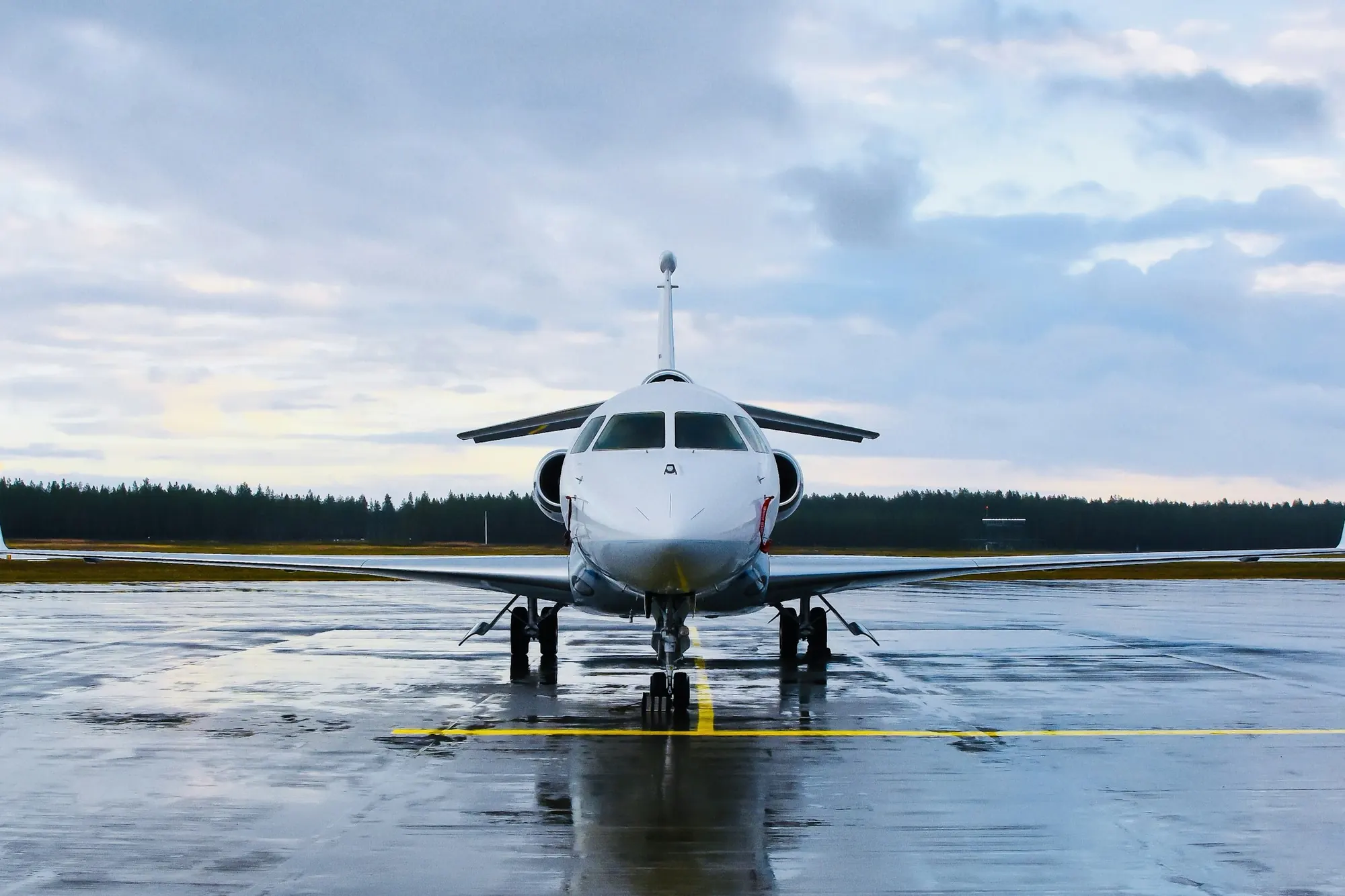 A business jet on a rain-soaked runway, seen head-on